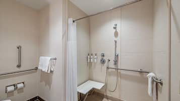 Un baño con ducha, inodoro y barras de apoyo.