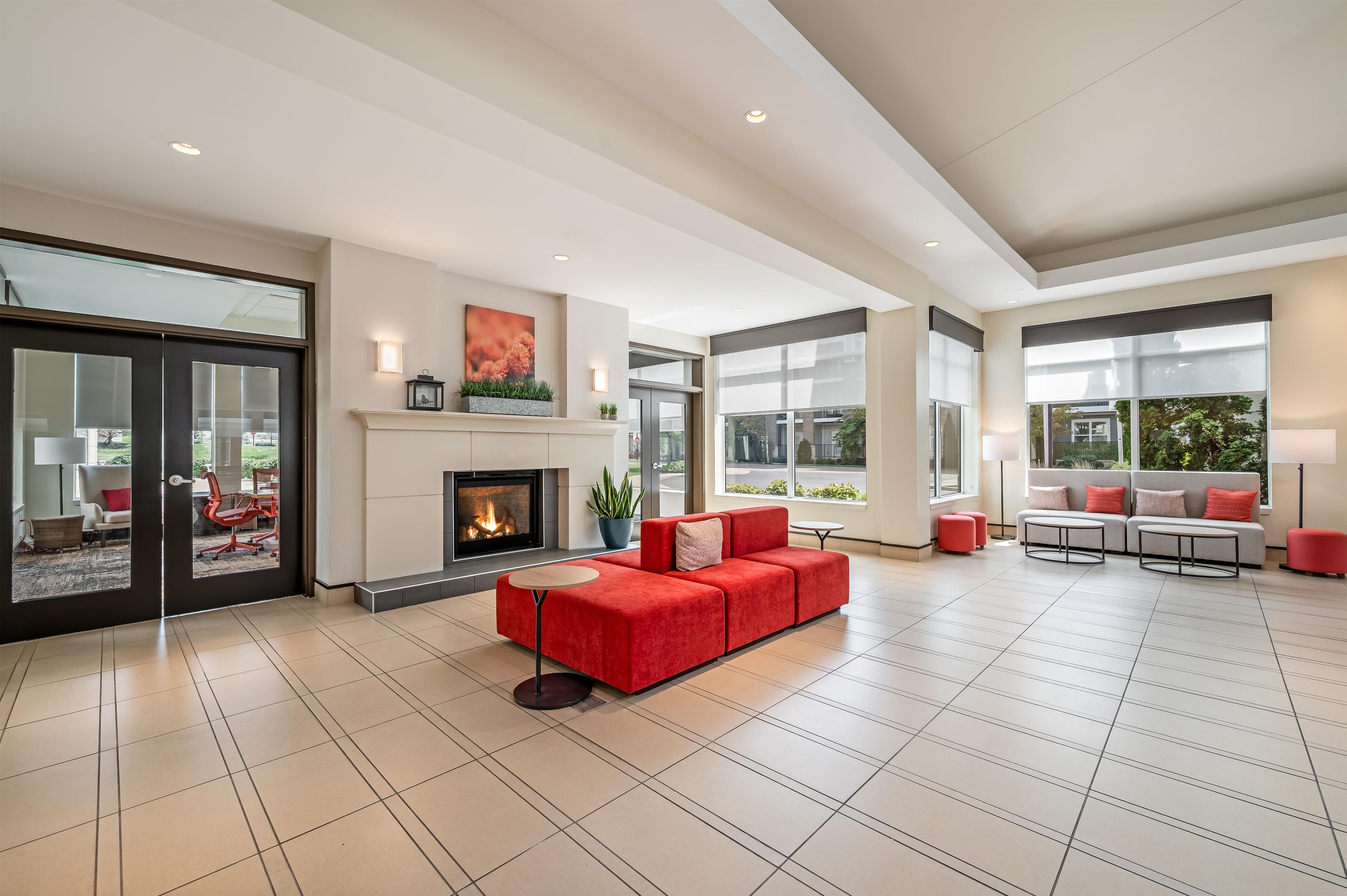 Amplia sala de estar con chimenea, sofás rojos y grandes ventanales con vistas al exterior.