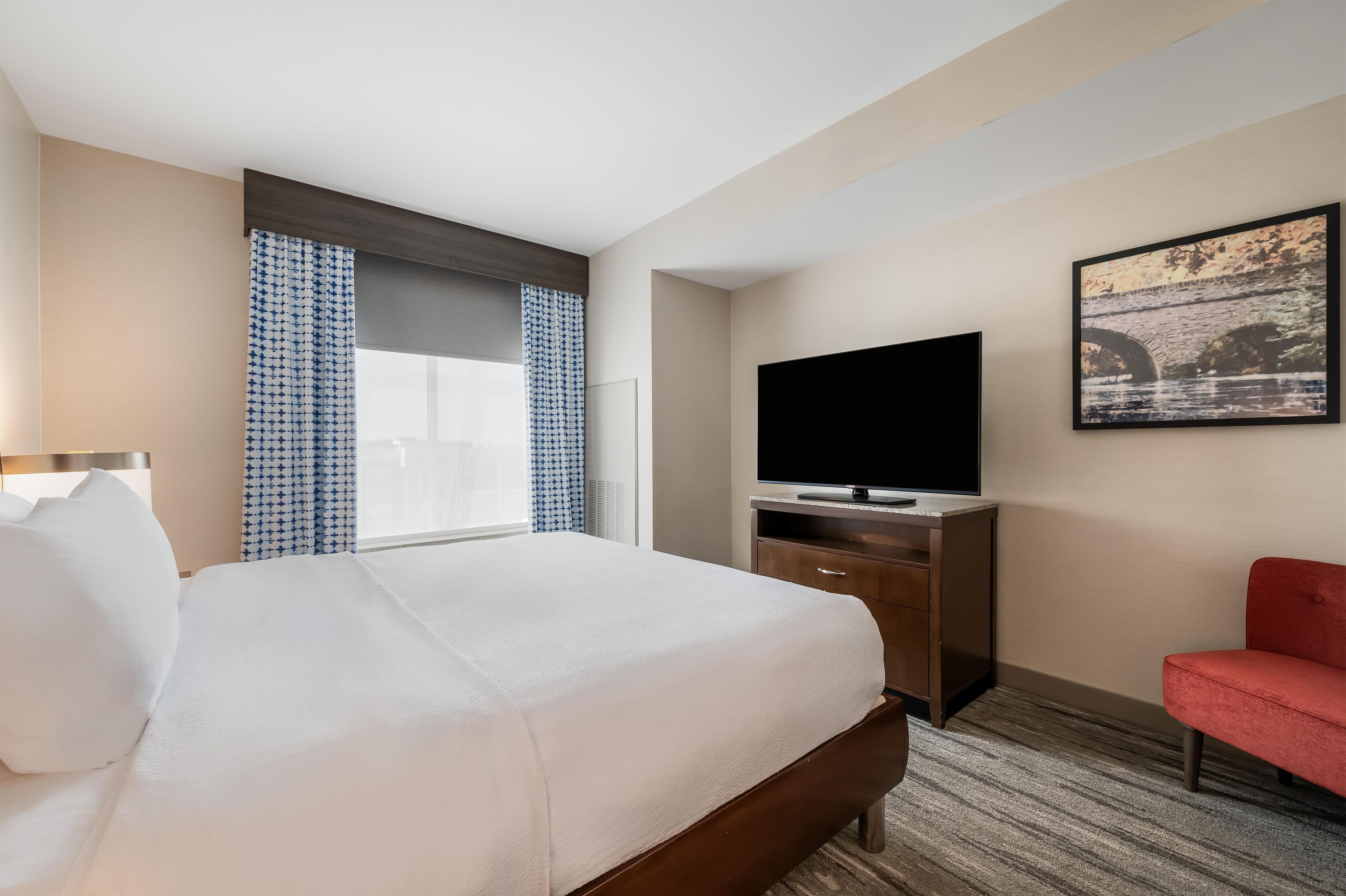 Una habitación de hotel con una cama, televisión, escritorio y una silla.