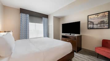 Una habitación de hotel con una cama, televisión, escritorio y una silla.