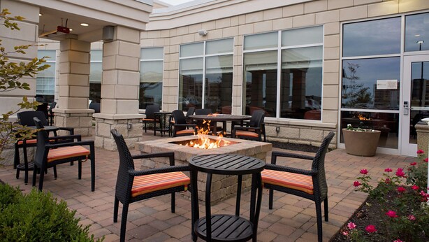 Un patio exterior con una fogata, asientos y vistas del edificio.