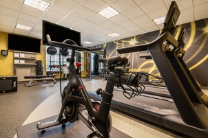 Un gimnasio con equipo de ejercicio, incluyendo una bicicleta estática, una cinta de correr y pesas.