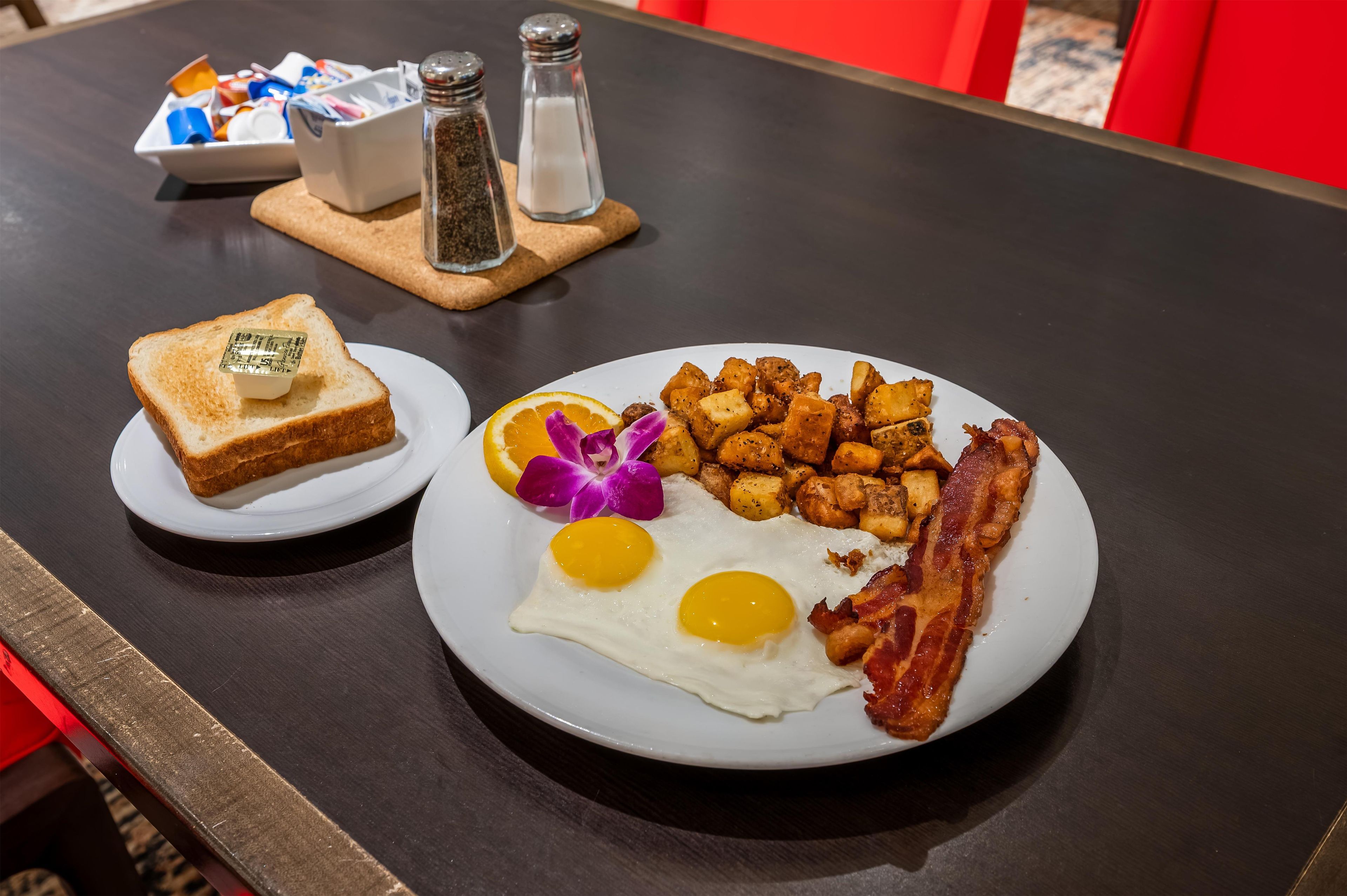A breakfast plate with toast, eggs, bacon, and potatoes.