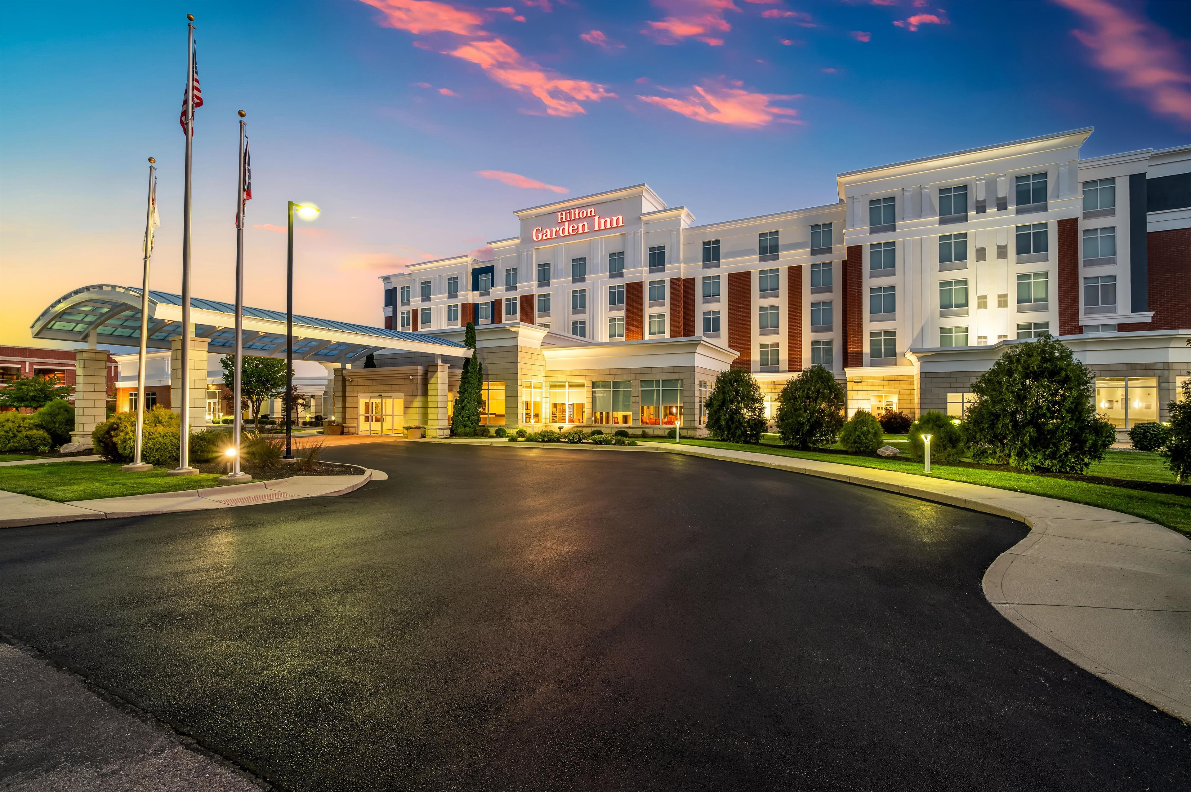A Hilton Garden Inn with a modern architectural design, featuring a large entrance and a well-lit driveway.