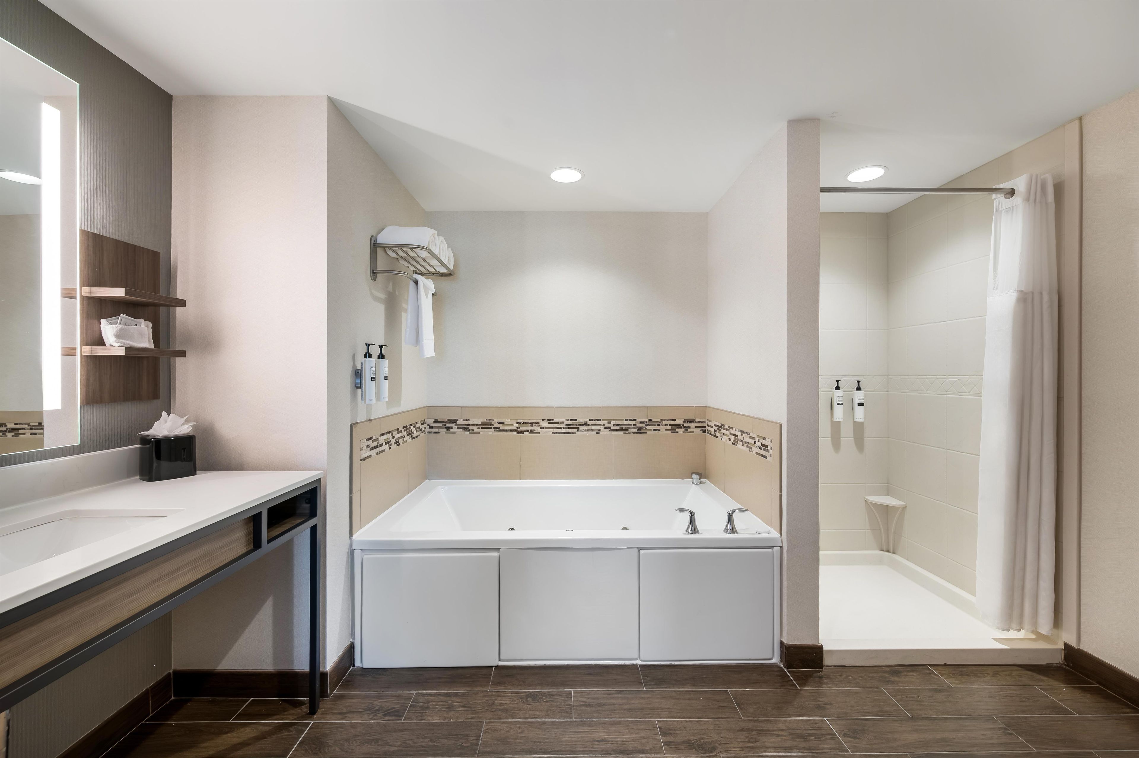 Un baño moderno con una bañera grande, una zona de ducha y un tocador con espejo.