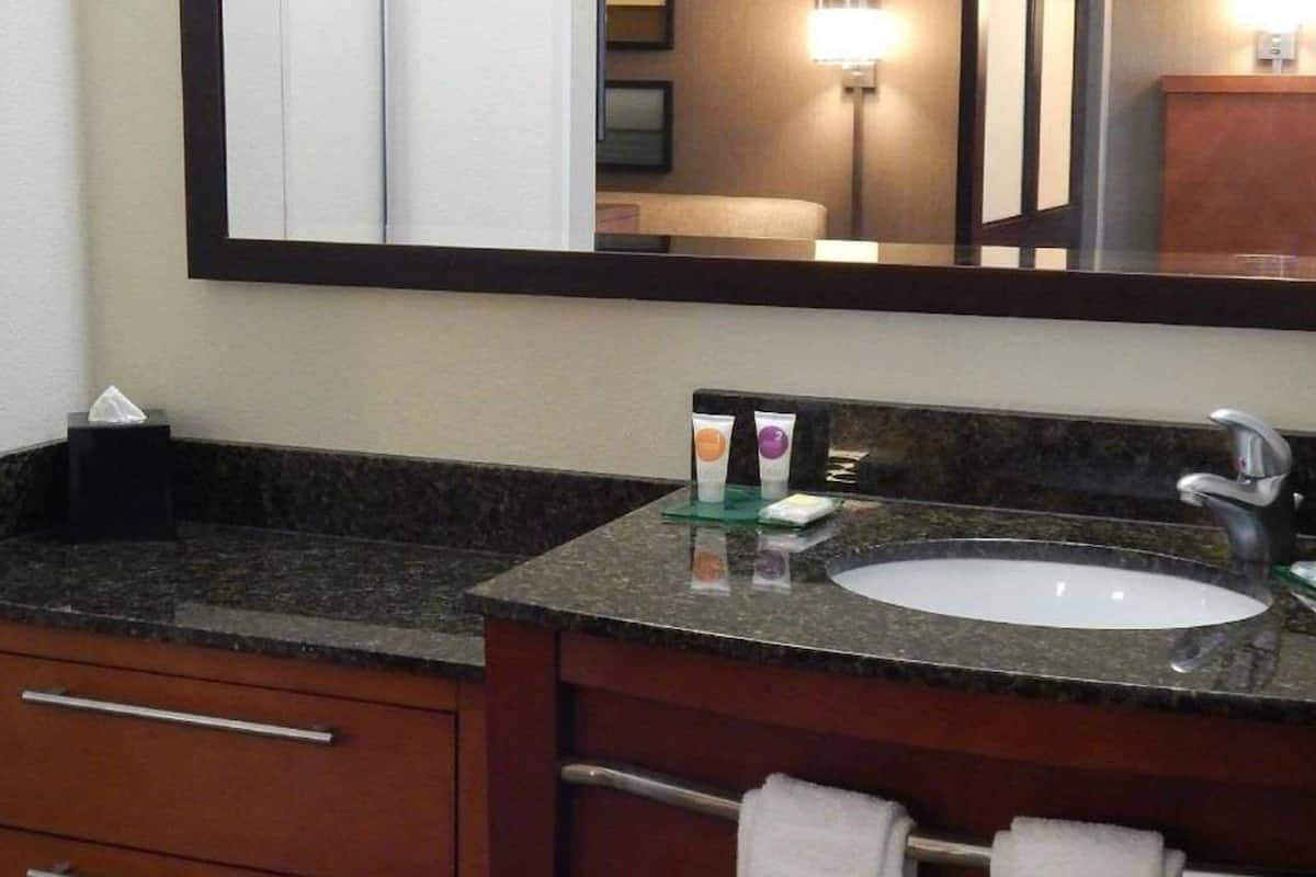 A bathroom with a granite countertop, a sink, a mirror, and a towel rack.