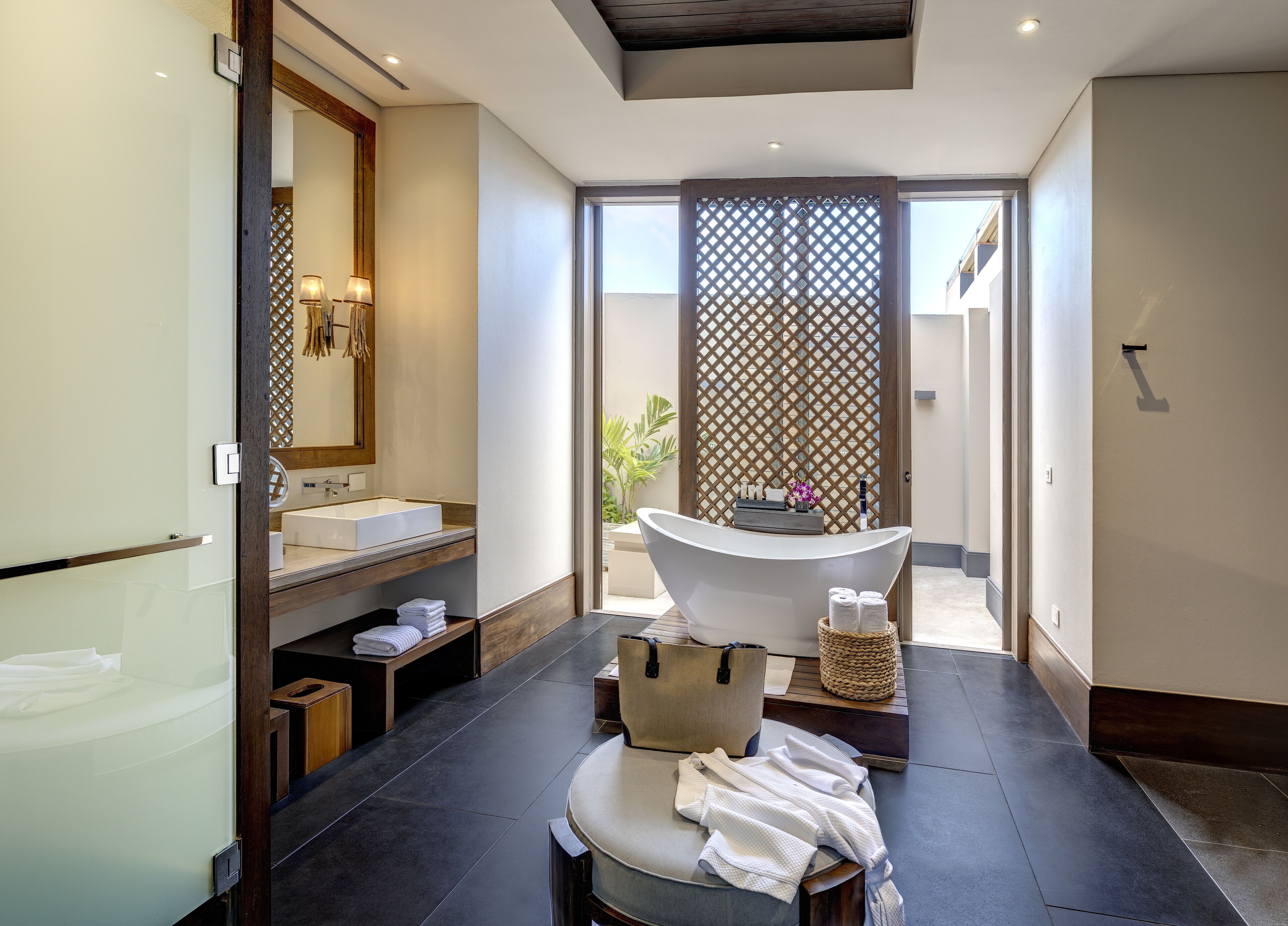 A modern bathroom with a freestanding bathtub, a large mirror, and a vanity with a sink.