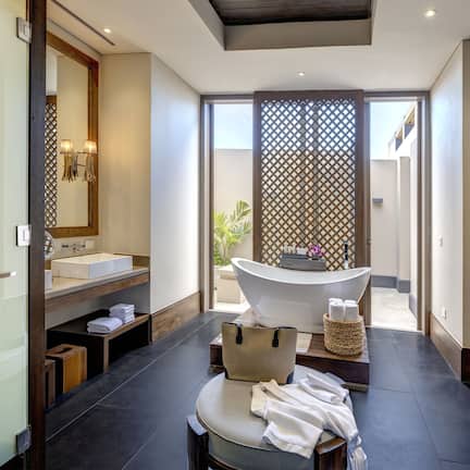 A modern bathroom with a freestanding bathtub, a large mirror, and a vanity with a sink.