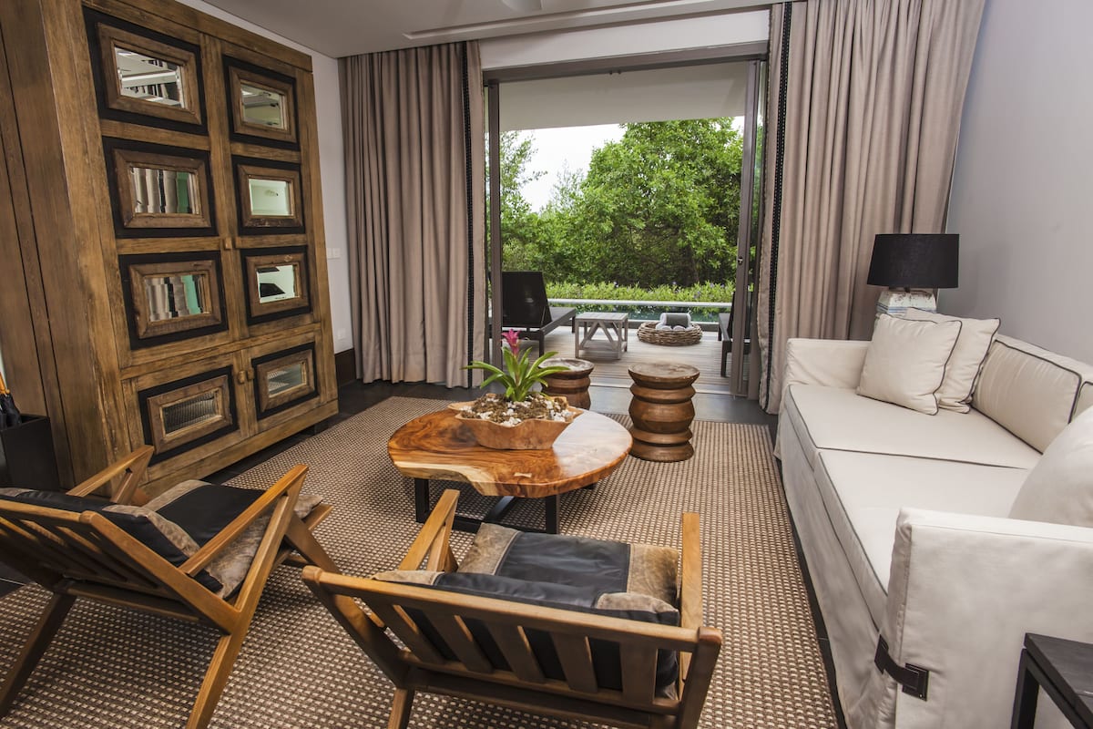A modern living room with a sofa, chairs, a coffee table, and a wooden cabinet with mirrors.