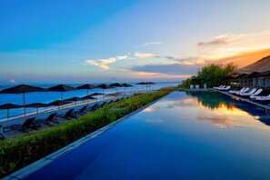 A poolside area with lounge chairs and umbrellas, overlooking the sea. - NIZUC Resort and Spa (Cancun)