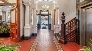 A grand hallway with a tiled floor, a chandelier, and a staircase with a wooden railing.