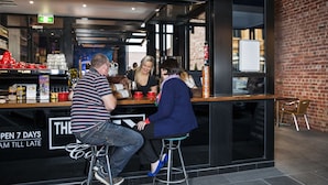 A bar area with stools, a counter, and a brick wall.