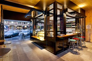Um café moderno com vitrine de vidro, mesas ao ar livre e vista para a rua.