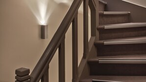 Un escalier doté d’une rampe et d’un éclairage fixé au mur.