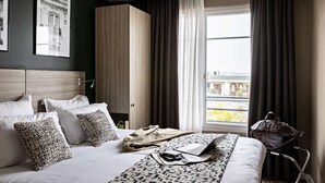 Une chambre d’hôtel avec un lit, un ordinateur portable, un sac à main et une vue sur la ville grâce à de grandes fenêtres.