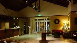 Eine Lobby mit einer Rezeption, einem runden Tisch mit Stühlen, einem roten Sofa und einer Wanduhr.