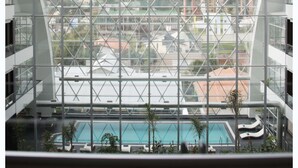A modern building with a glass facade and a pool area visible through the windows. - Casa Grande Hotel (La Paz)