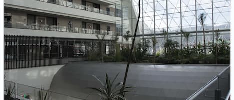 Ein modernes Gebäude mit Glasfassade, einem geschwungenen Balkon und Blick auf einen Parkplatz.