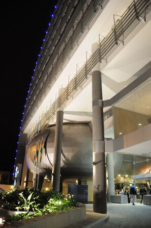 Un bâtiment moderne doté d’une façade incurvée, de larges piliers et d’un balcon agrémenté de balustrades.