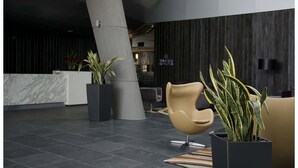 A modern lobby with a marble reception desk, a large pillar, and contemporary seating. - Casa Grande Hotel (La Paz)