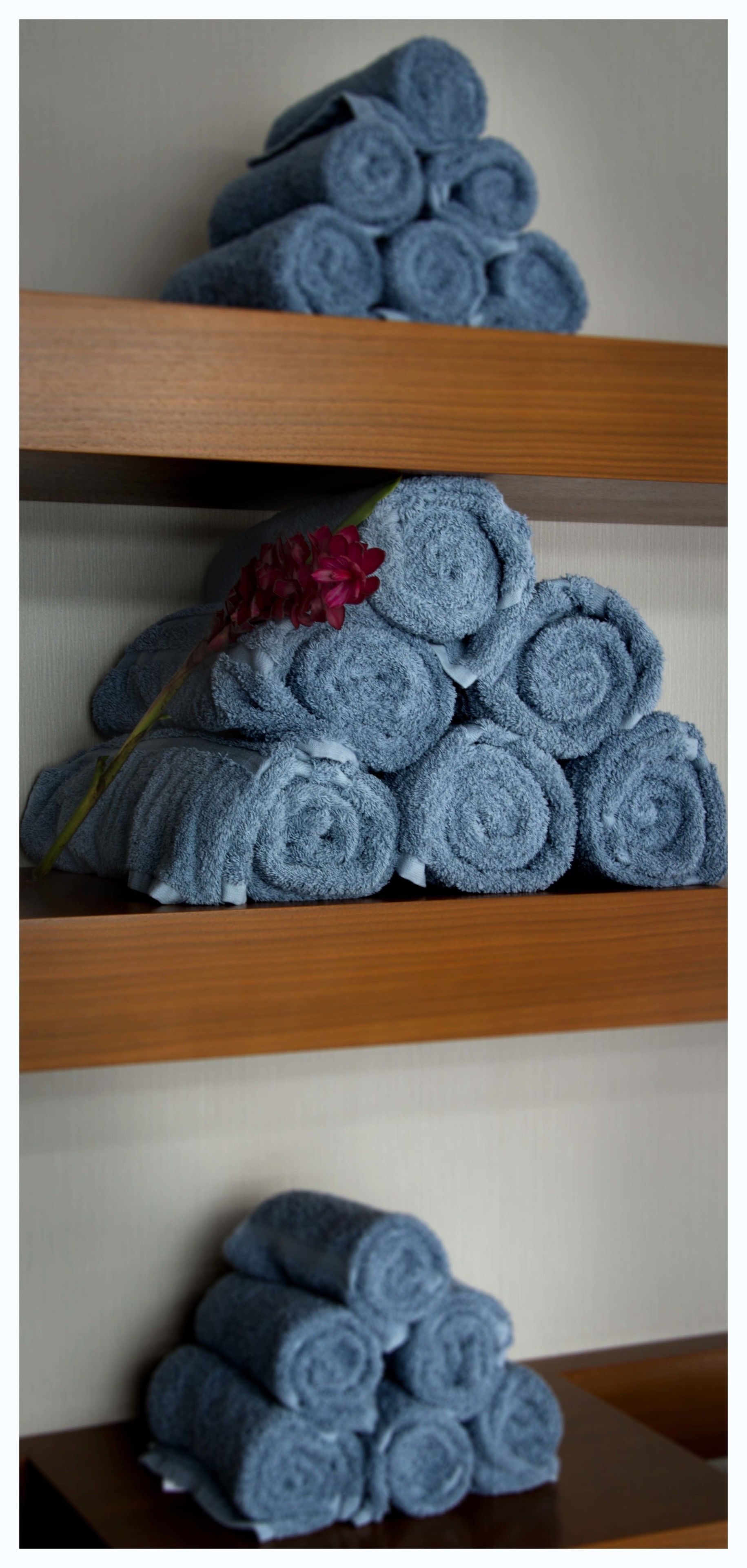 A stack of neatly rolled towels on wooden shelves.