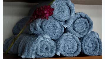A stack of neatly rolled towels on wooden shelves.