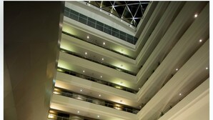 A multi-level atrium with a central staircase, seating areas, and potted plants. - Casa Grande Hotel (La Paz)