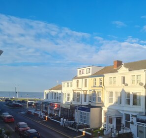 A coastal street with white buildings, a visible hotel, and parked cars. - Beverley Dean (Blackpool)
