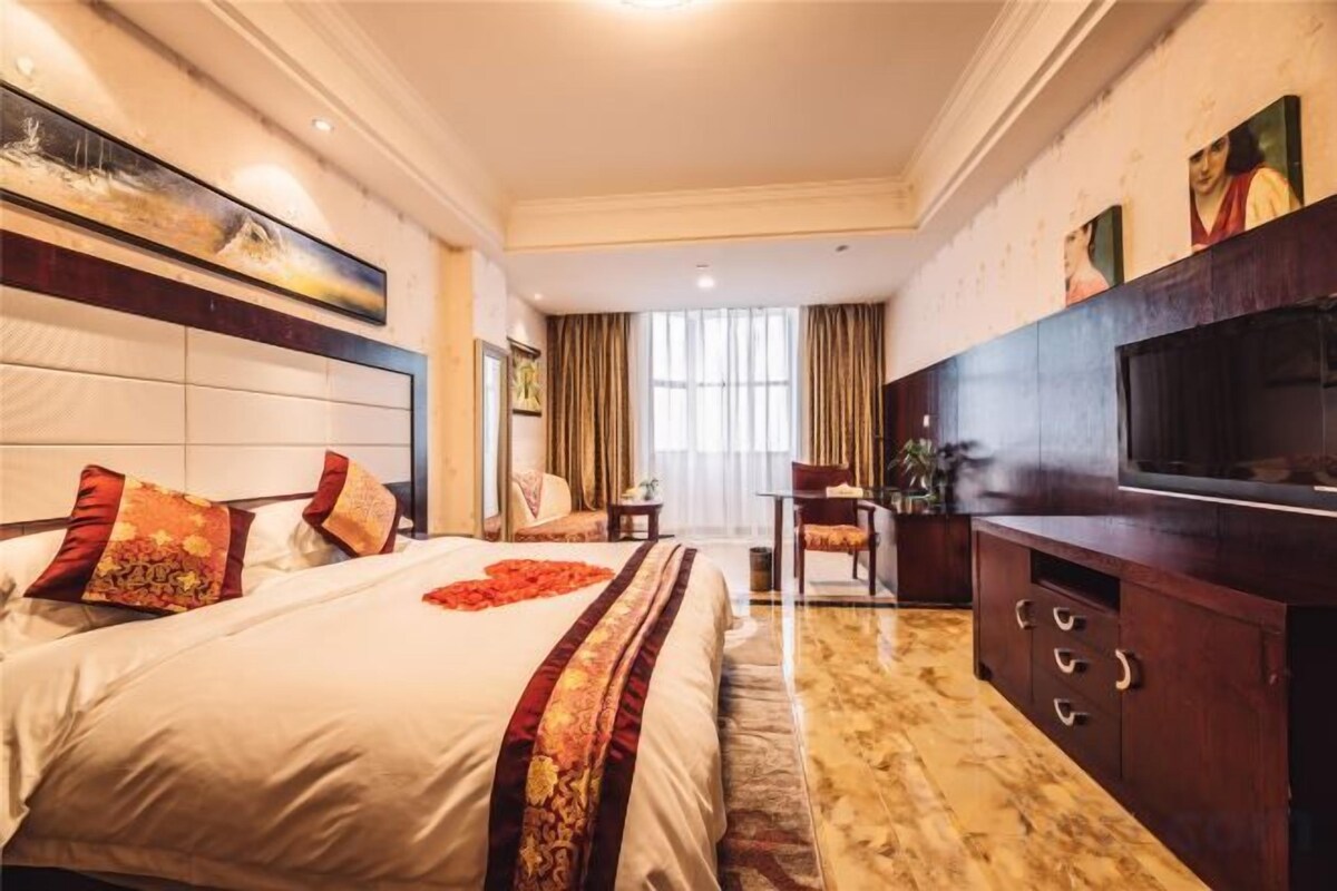 A hotel room with a large bed, a desk, a television, and a view of the outdoors.