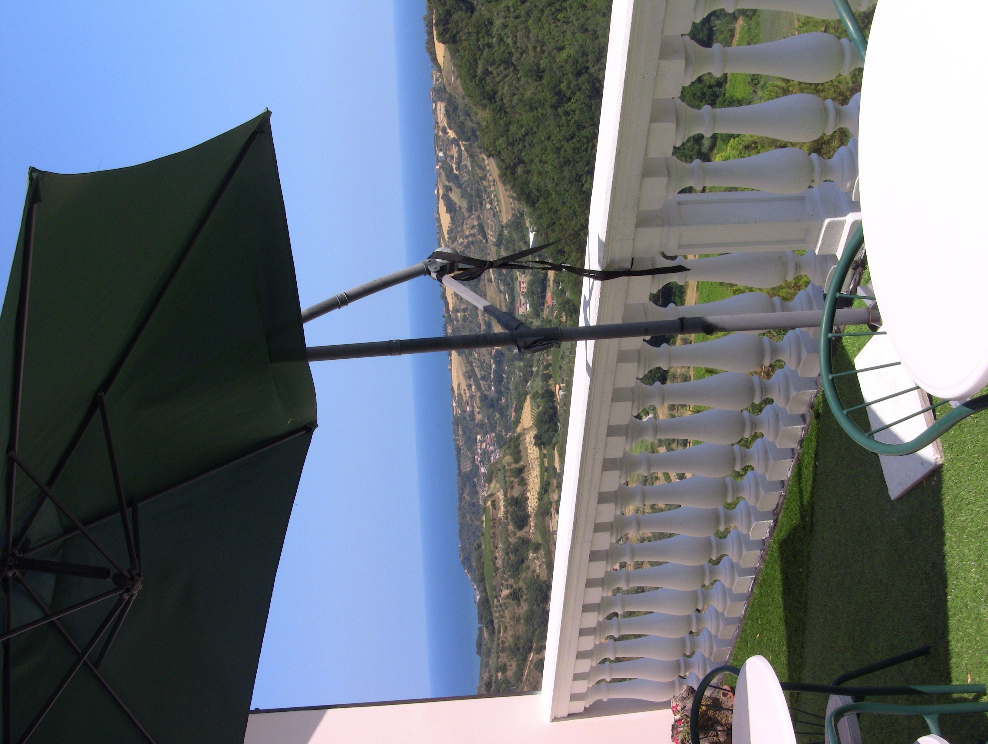 Une vue d’un paysage côtier avec une clôture blanche et des parasols verts.