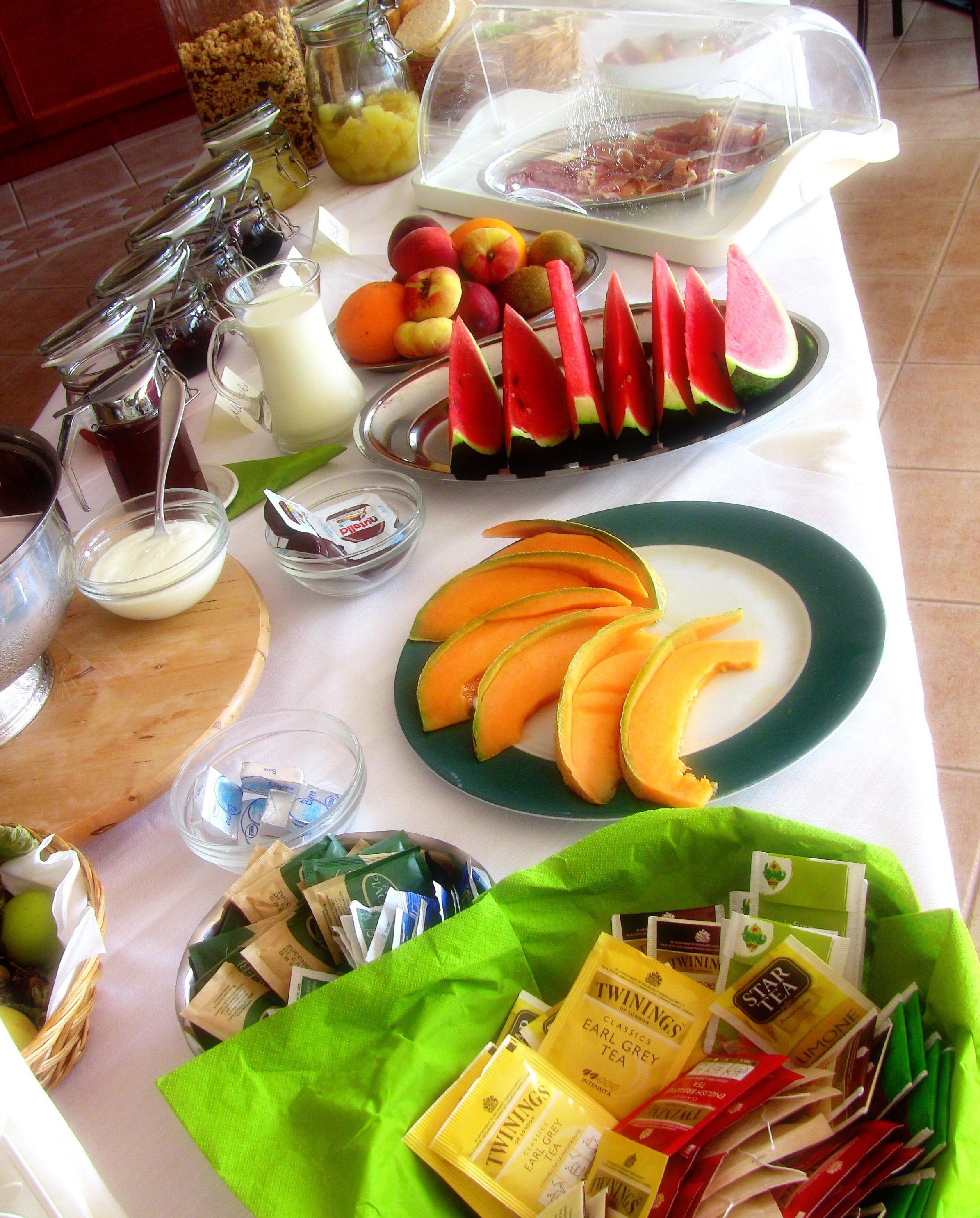 Un bufé de desayuno con diversas frutas, bebidas y opciones de té.