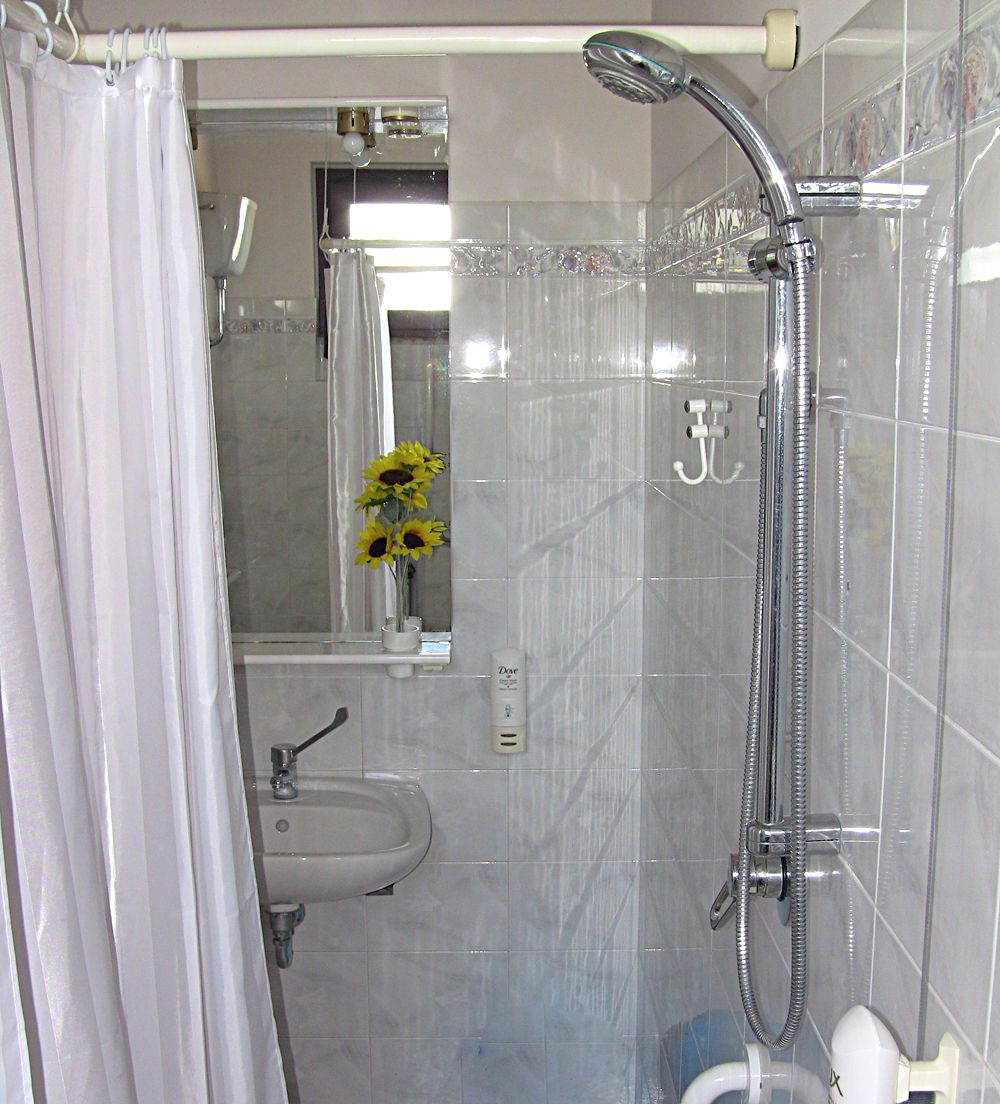 Ein Badezimmer mit Dusche, Waschbecken und Spiegel.