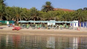 A beach with palm trees and beach umbrellas. - Il Corbezzolo (Cupra Marittima)