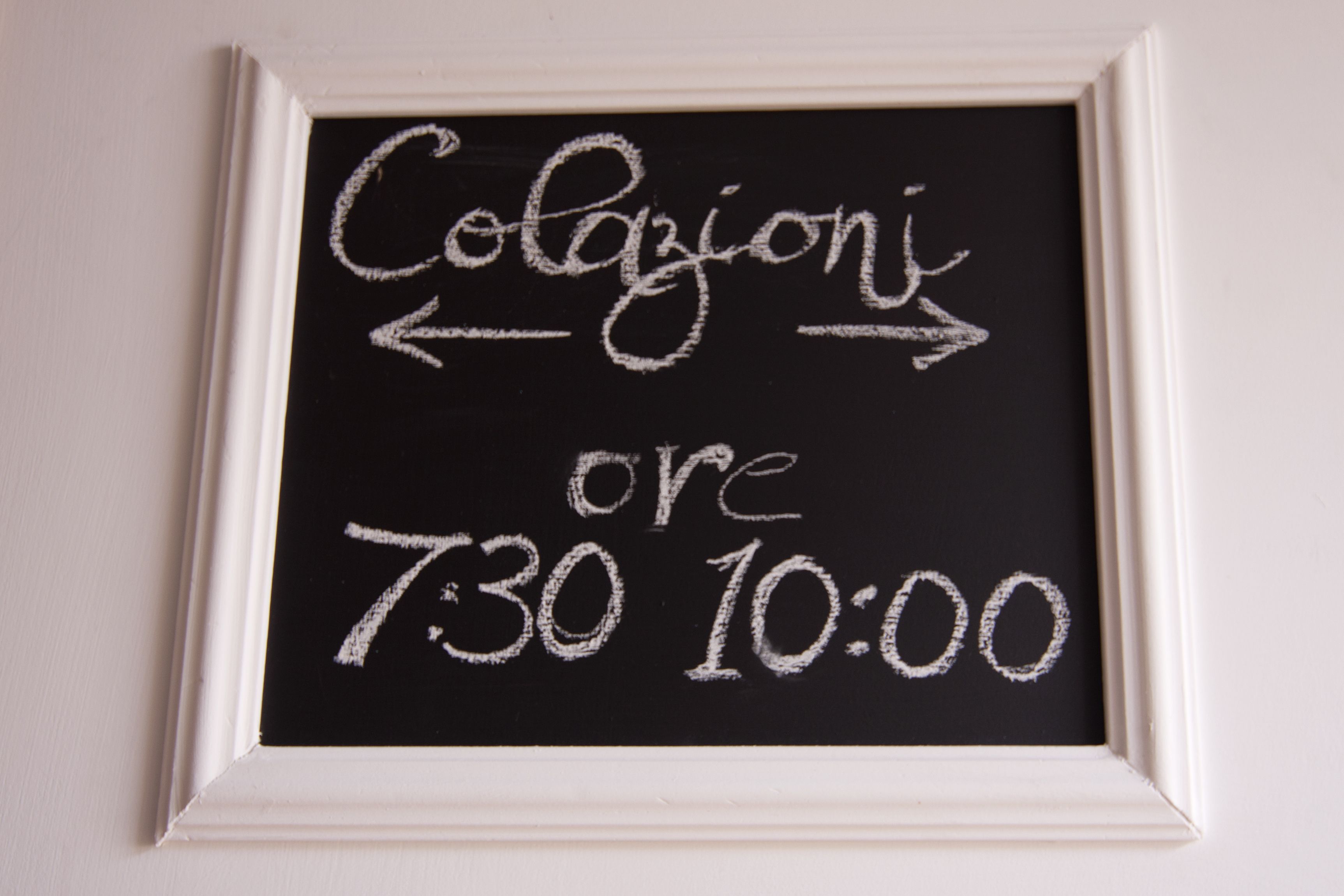 Una pizarra con escritura a tiza que indica 'Colazione' (desayuno) de 7:30 a 10:00.