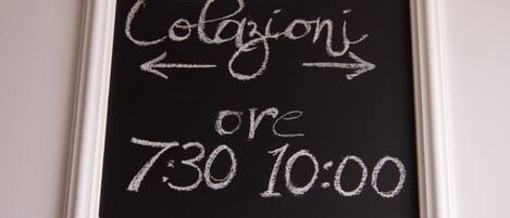 Una pizarra con escritura a tiza que indica 'Colazione' (desayuno) de 7:30 a 10:00.