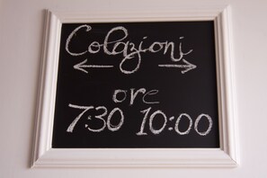 Quadro negro com escrita a giz indicando horário do café da manhã: 7h30–10h00.