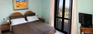 A bedroom with a bed, two bedside tables, a TV, and a window with a view. - Il Corbezzolo (Cupra Marittima)