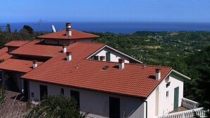 A multi-story building with red-tiled roofs and white walls, overlooking a coastal landscape. - Il Corbezzolo (Cupra Marittima)