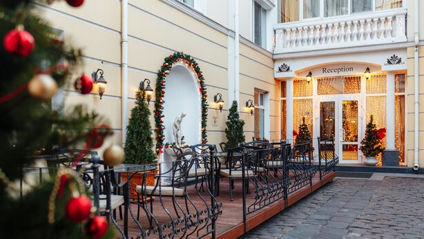 A reception area with a Christmas tree, outdoor seating, and a statue. - Odesskiy Dvorik (Odesa)