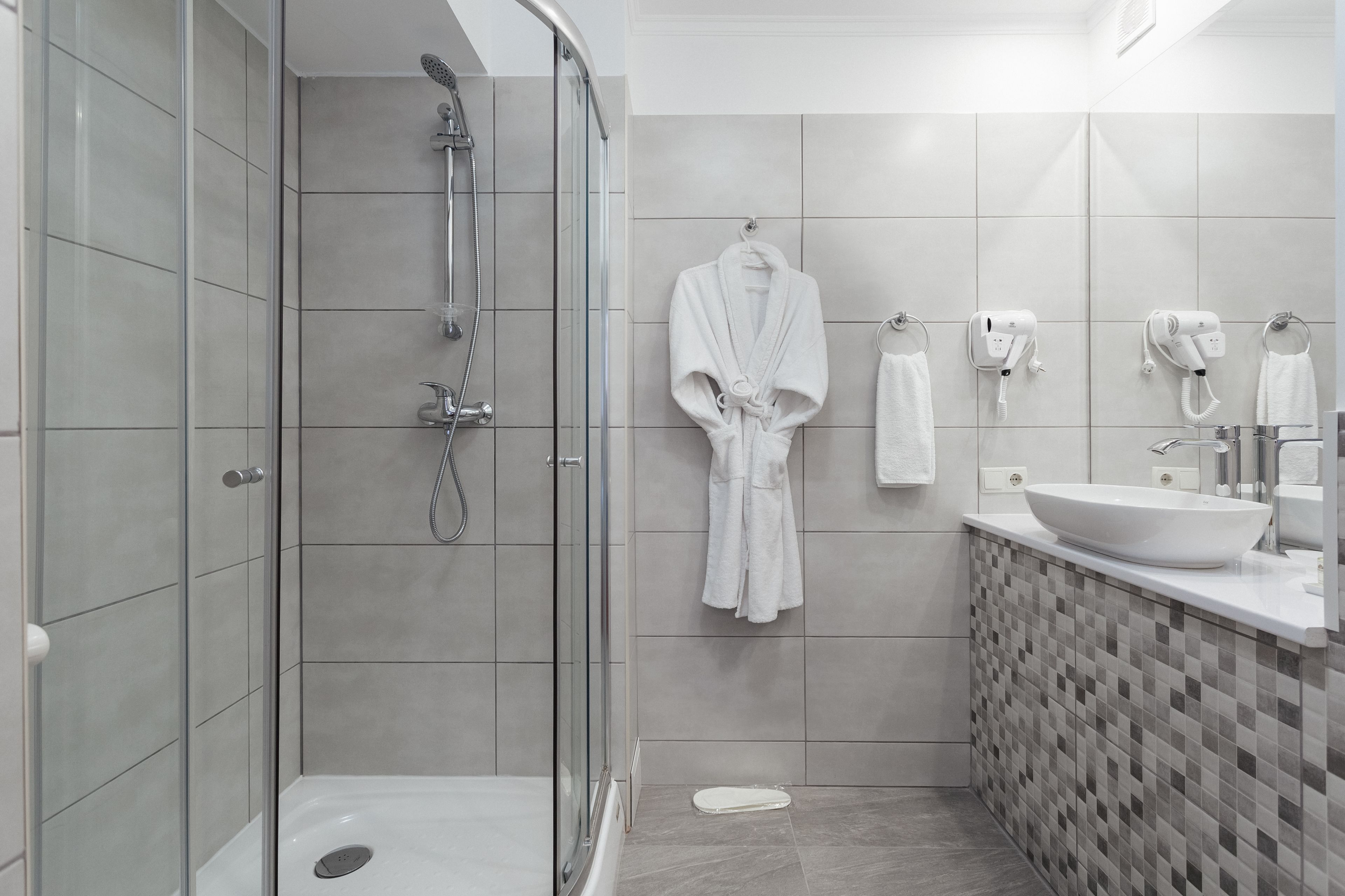 A modern bathroom with a glass-enclosed shower, a white sink, and a tiled backsplash.