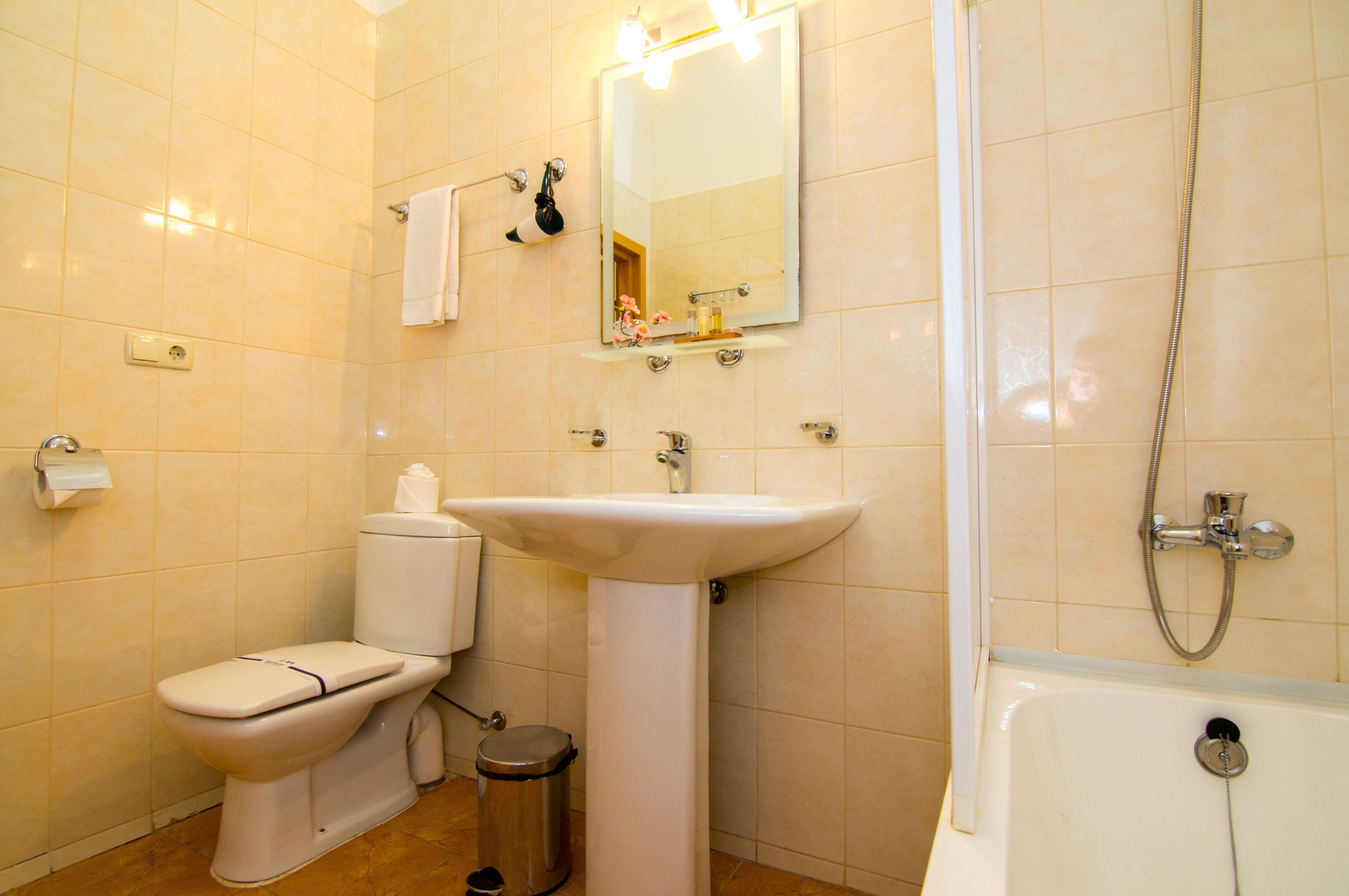 A bathroom with a toilet, sink, mirror, and bathtub.