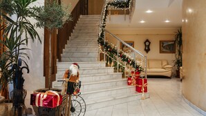 A grand staircase with a Christmas tree and garlands, leading to a second floor. - Odesskiy Dvorik (Odesa)
