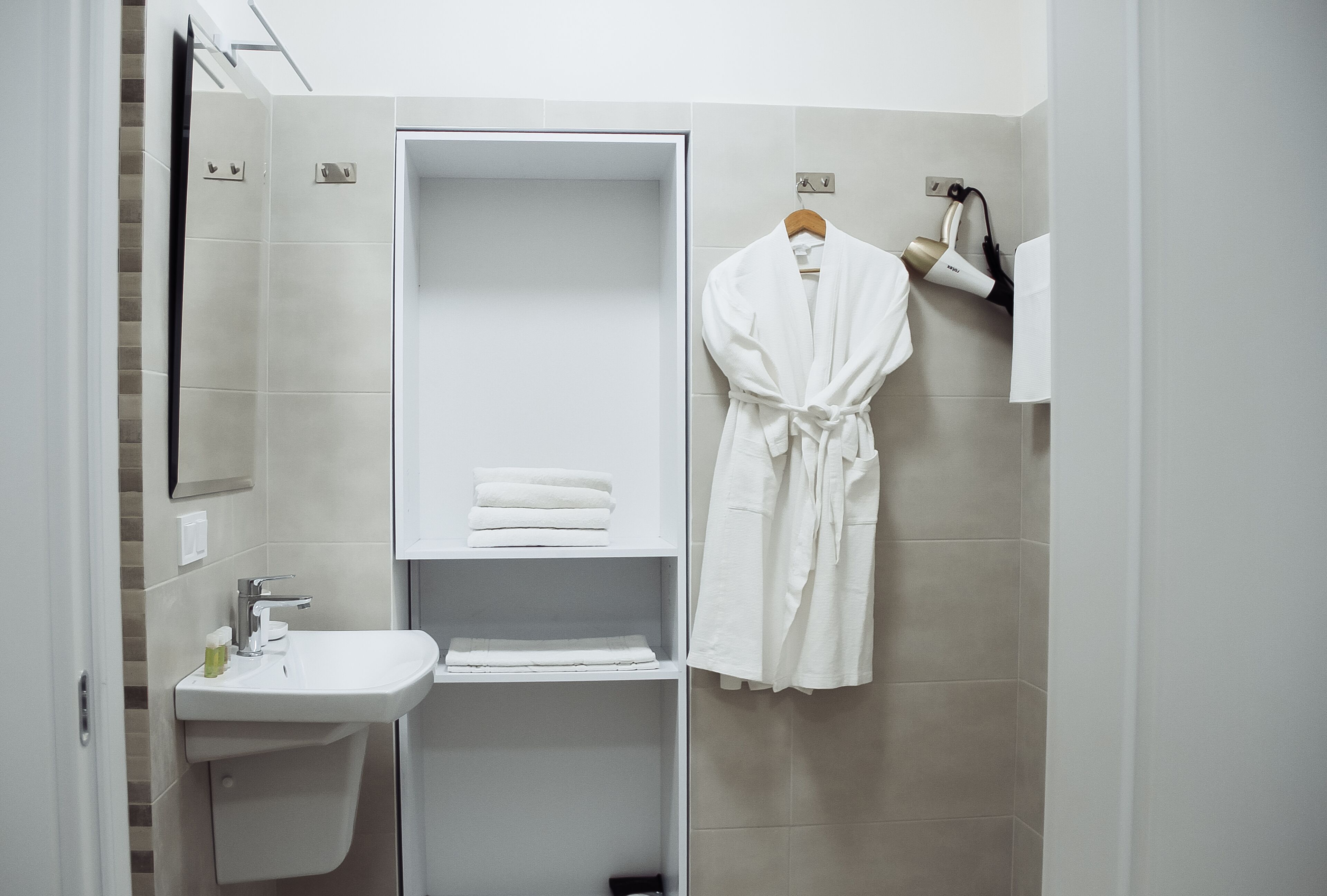 Un baño moderno con ducha integrada, un lavabo y una bata colgada en la pared.
