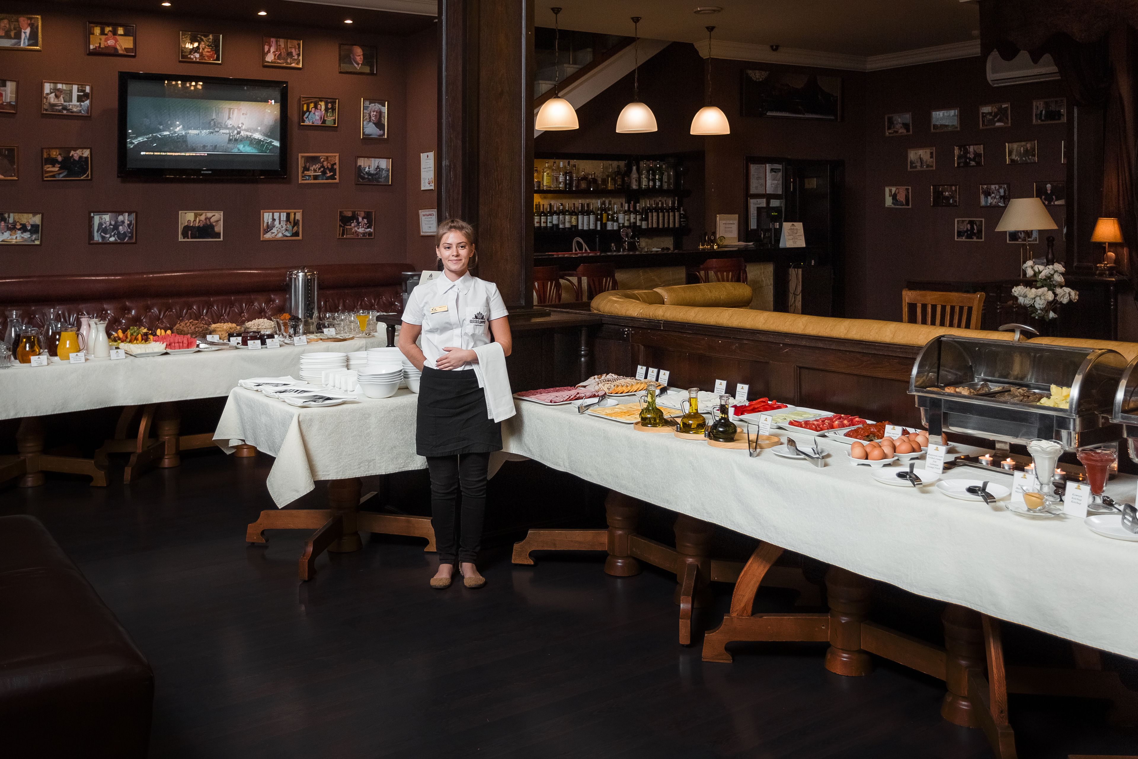 Un restaurante con varias mesas, una zona de bar y una pantalla de televisión en la pared.