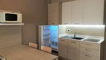A modern kitchen with a built-in microwave, refrigerator, and sink.