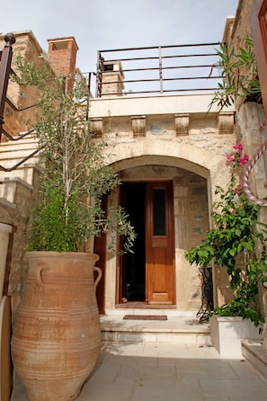 Un edificio de piedra con una puerta de madera y una maceta grande de terracota.