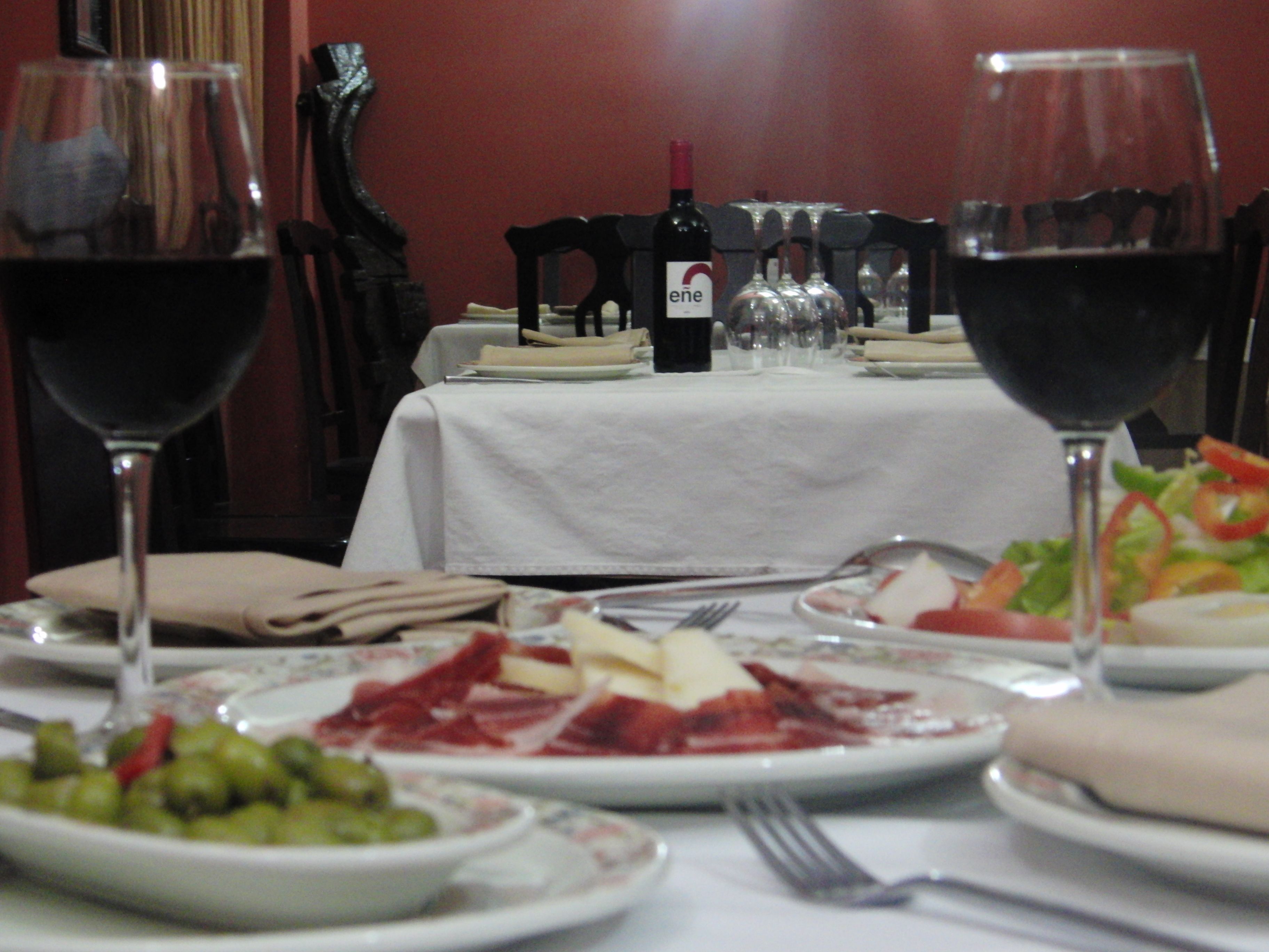 A dining table set with plates of food, wine glasses, and a bottle of wine.