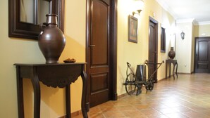 A hallway with a large vase on a table, a bicycle cart, and a door. - Hostal Pechi (Huevar del Aljarafe)