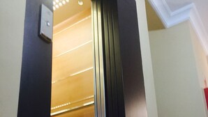 An elevator with a metallic interior and a light fixture above the door. - Hostal Pechi (Huevar del Aljarafe)