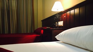 A hotel room with a bed, a nightstand, a lamp, and a curtain. - Hostal Pechi (Huevar del Aljarafe)